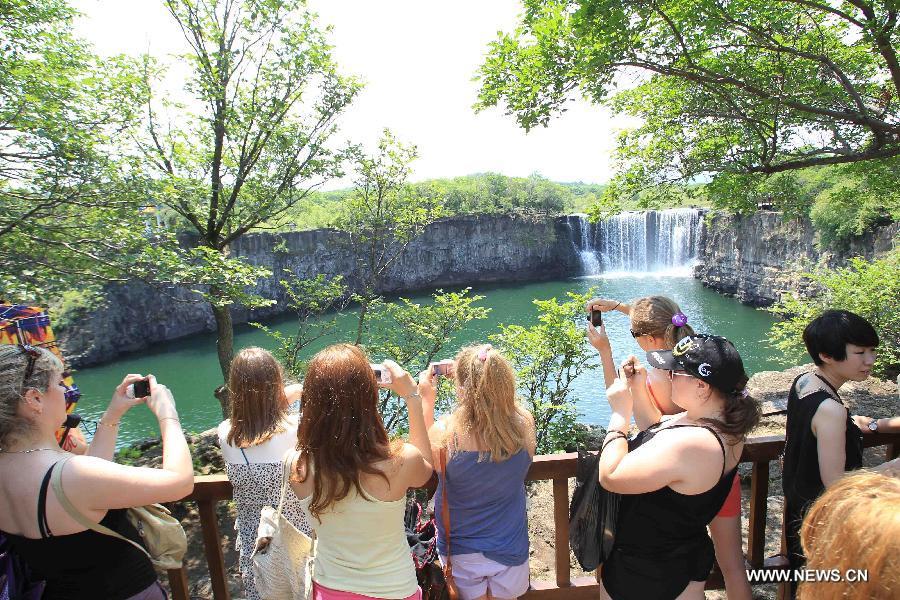 Russian visitors take photos of the Diaoshuilou Waterfall at the Jingpo Lake scenic area in Mudanjiang, northeast China's Heilongjiang Province, July 7, 2012. The China-Russia cooperation in tourism has substantially progressed, which also has promoted bilateral understandings and exchange of culture in recent years. The Year of Chinese Tourism in Russia in 2013 will be inaugurated by Chinese President Xi Jinping when he visits Moscow later this month. (Xinhua/Zhang Yanhui)