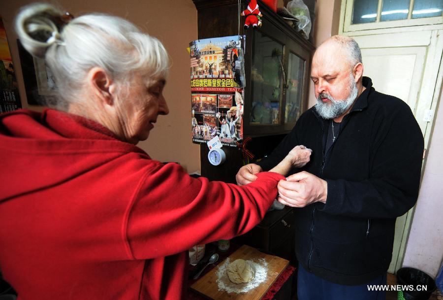 Eremin Sergei helps roll up his mother's sleeves as she prepares for lunch in the dormitory on the Sun Island Sun Island in Harbin, capital of northeast China's Heilongjiang Province, March 15, 2013.(Xinhua/Wang Jianwei) 