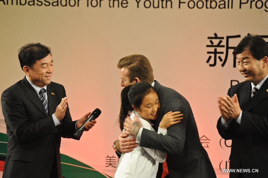British footballer David Beckham (2nd R) hugs with a girl during a press conference in Beijing, capital of China, on March 20, 2013. David Beckham came to China as the ambassador for the youth football Program in China and the Chinese Super League (CSL). (Xinhua/Cao Can) 