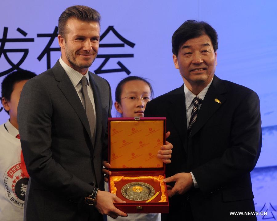British footballer David Beckham (L) gets a gift from Wei Jixiang, secretary of Football Management Center of General Administration of Sport of China, during a press conference in Beijing, capital of China, on March 20, 2013. David Beckham came China as Ambassador for the Youth Football Programme in China and the Chinese Super League (CSL). (Xinhua/Gong Lei)