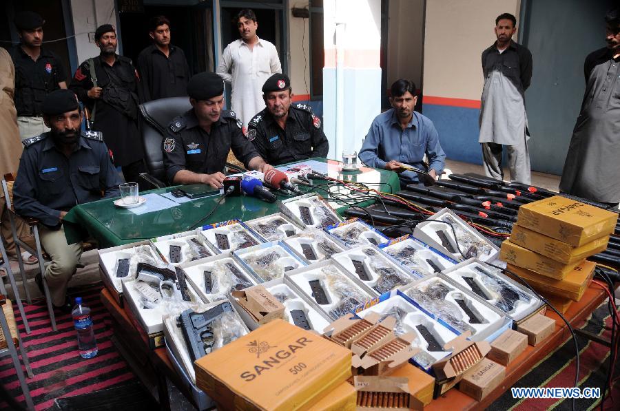 Policemen display seized weapons to media at a police station in northwest Pakistan's Peshawar on March 19, 2013. Police arrested two suspects who tried to smuggle weapons and ammunitions from Peshawar to Punjab province, local media reported. (Xinhua/Ahmad Sidique) 