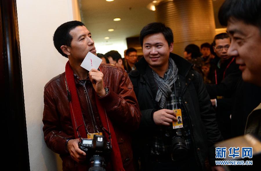 Photo shows a journalist holding a card with the number one. On March 4 the panel discussion of artists attracted many journalists. With the purpose of keeping the interviews in order, the journalists were requested to queue up and make interviews in accordance with the number of the card they received. (Xinhua/ Jin Liangkuai)