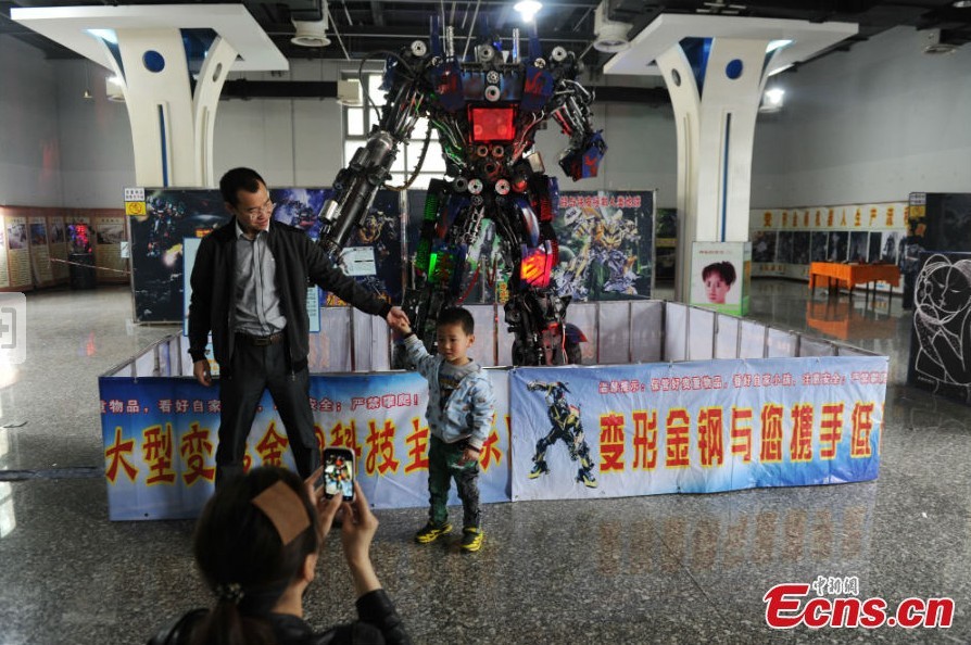 A boy takes photos with a robot statue at an exhibition featured on characters of the American science fiction action film Transformers in Chengdu, Southwest China's Sichuan Province, March 19, 2013. The statues were made of parts from written-off vehicles. (CNS/Zhang Lang)
