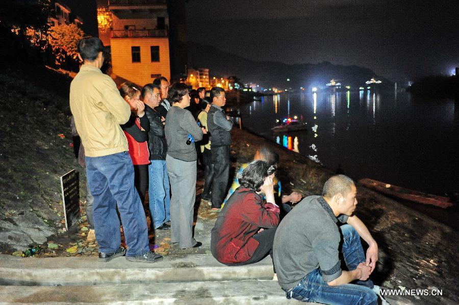 Family members of victims and locals wait ashore as a crane vessel salvages a capsized ferry at the local section of the Minjiang River at Xiadao Town in Nanping, southeast China's Fujian Province, March 20, 2013. Three people were confirmed dead and 12 remained missing as the ferry sank Wednesday morning in atrocious weather. (Xinhua/Lin Shanchuan)