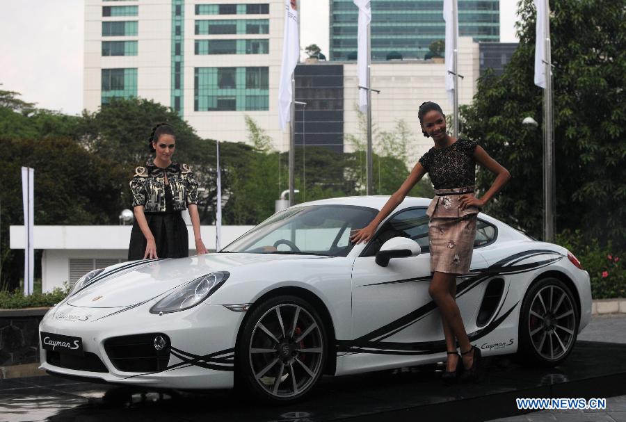 Models stand beside a Porsche Cayman S at a launching ceremony in Jakarta, Indonesia, March 19, 2013. Porsche Indonesia launched Cayman and Cayman S on Tuesday. (Xinhua/Zulkarnain) 