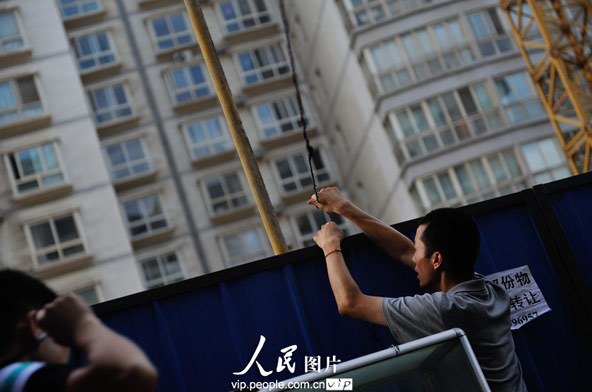 Zhao prepares the light of open-air part of the restaurant when it gets dark. As the pergola was stolen some days before, the lamp wires can only be supported by the scaffolding they borrowed from the construction site nearby.(photo/vip.peolpe.com.cn)