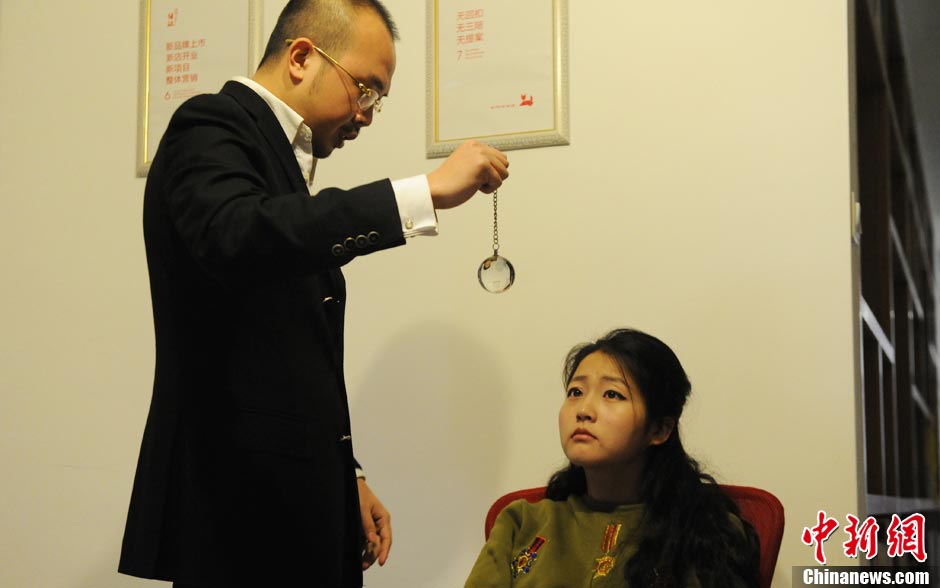 Tang Tang asks a woman to focus on the crystal ball in his deep sleep studio. (CNS/ Yang Huafeng)