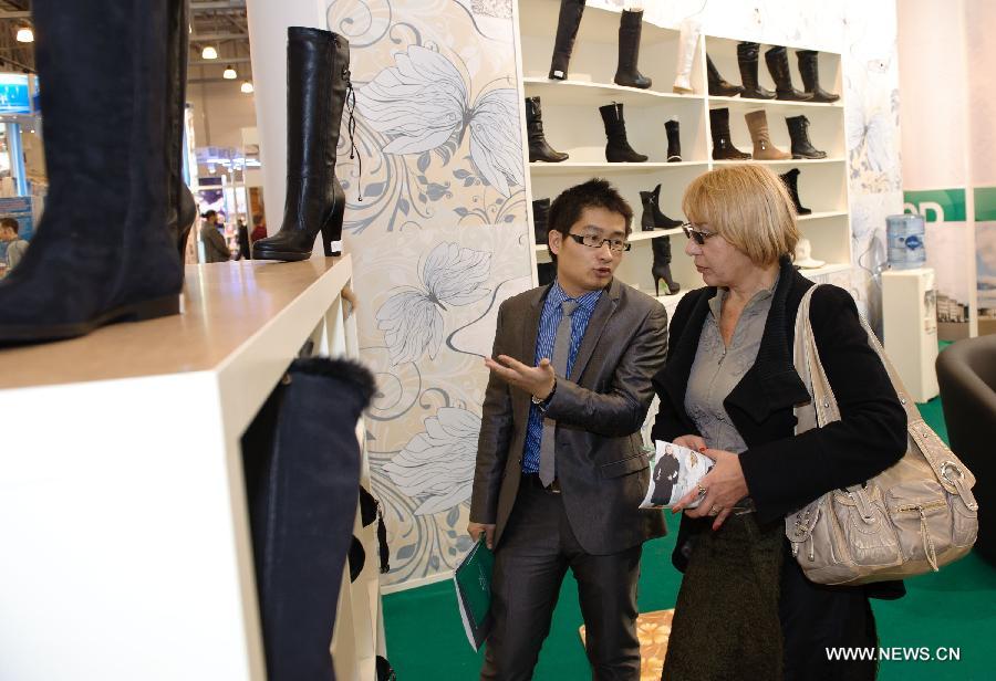 File photo taken on Oct. 19, 2011 shows a Chinese trader (L) introduces shoes made in China at the Greenwood International Trade Center in Moscow, Russia. The Greenwood International Trade Center, a 350-million-U.S.-dollar program financed by China Chengtong Development Group, started operation in Moscow in Spet. 2011. The Greenwood covers an area of 200,000 square meters, with a total construction area of 132,600 square meters. The trade center, the largest Chinese investment project in the field of commerce in Russia, serves as a platform for Chinese products to enter the Russian market. (Xinhua/Jiang Kehong) 