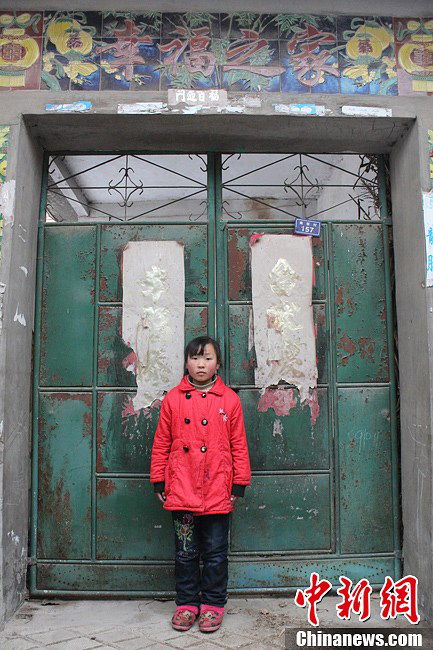Song stands in front of the door of her home. The words “A happy family”read on the wall above the door tingles. (Chinanews.com / Zhou Panpan)