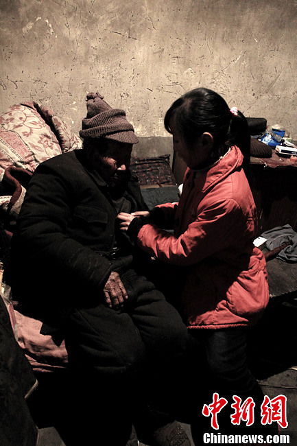 Song tucks her grandfather into bed after dinner. (Chinanews.com / Zhou Panpan)