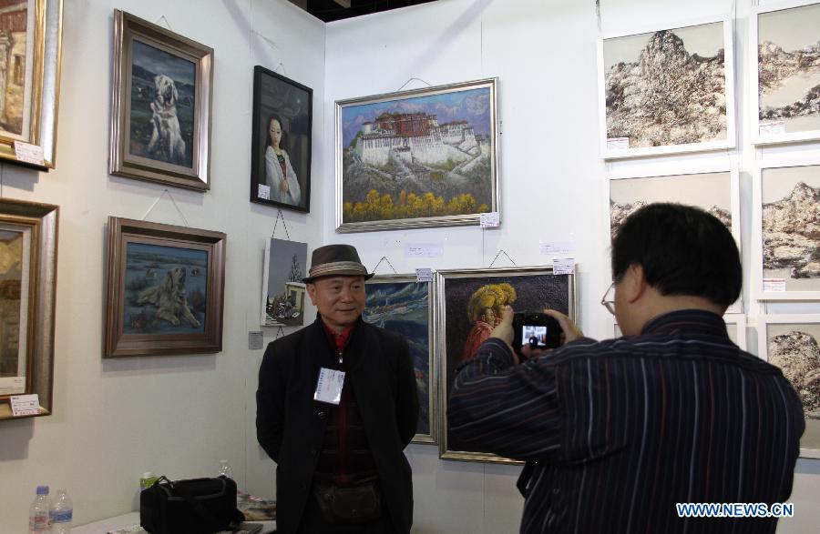 Chinese artist Lin Yue poses with his artworks on view in New York City, the United States, on March 21, 2013, during the New York Art Expo which is the world's largest fine art trade show for 35 years. (Xinhua/Wang Chengyun) 