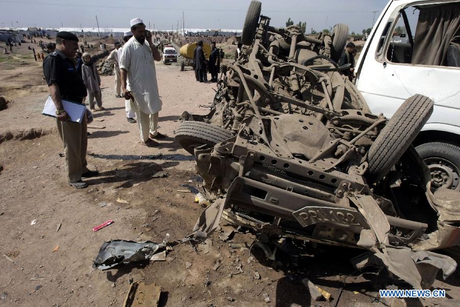 Security officials examine damaged vehicles at the site of a bomb attack at the Jalozai refugee camp in northwest Pakistan's Nowshera on March 21, 2013. At least 12 people were killed and 35 others injured when a bomb hit a refugee camp in Nowshera on Thursday morning, local officials said. (Xinhua Photo/Umar Qayyum)