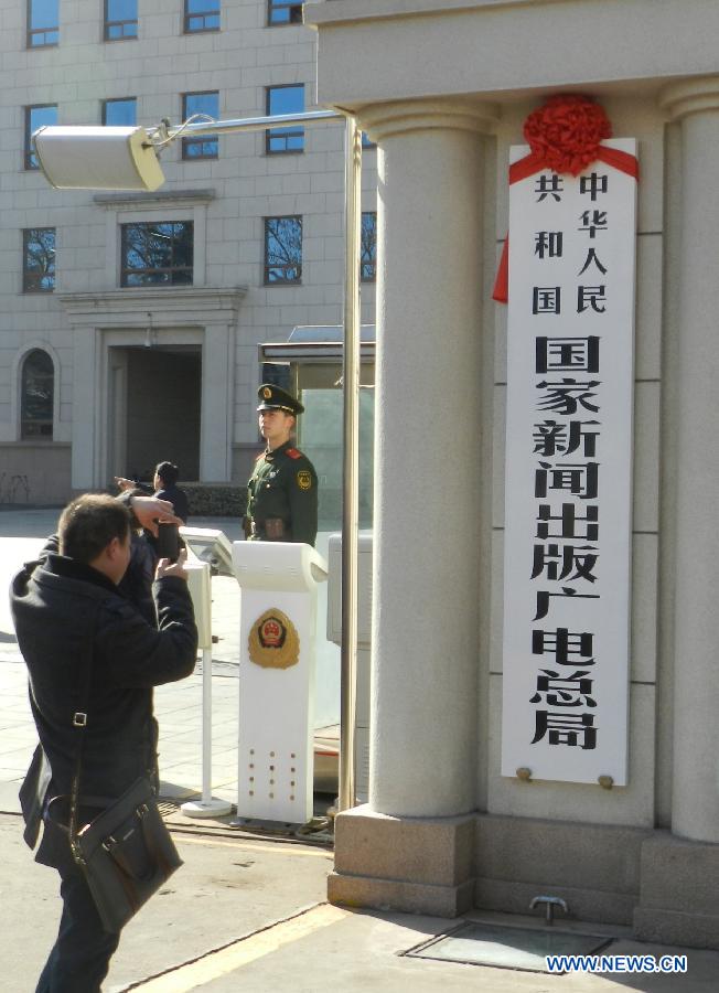 A tourist takes photos of the newly-hung nameplate State General Administration of Press, Publication, Radio, Film and Television in Beijing, capital of China, March 22, 2013. China's National People's Congress, the country's top legislature, has adopted a cabinet reshuffle plan in which two media regulators, the General Administration of Press and Publication and the State Administration of Radio, Film and Television, were merged into a single entity to oversee the country's press, publication, radio, film and television sectors. (Xinhua/Wang Zhen)