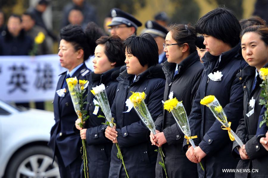 People hold chrysanthemum flowers to bid farewell to Song Yang, the late bus driver who managed to protect passengers while he was having a stroke, in Jinan, capital of east China's Shandong Province, March 22, 2013. Song experienced a sudden brain hemorrhage while he was driving a long-distance bus carrying 33 passengers on a highway in Chiping County on the morning of March 9. He managed to slow down and park in the highway's breakdown lane, then tried his best to pull the handbrake and turn on the hazard lights. The 34-year-old driver passed away on March 20 despite being treated for days in the hospital. (Xinhua/Guo Xulei)
