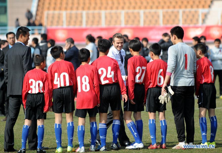 British soccer player David Beckham (C) shakes hands with students at the Qingdao Tiantai Stadium in Qingdao, east China's Shandong Province, March 22, 2013. Beckham visited Qingdao Jonoon Soccer Club as the ambassador for the youth football program in China and the Chinese Super League Friday. (Xinhua/Li Ziheng)