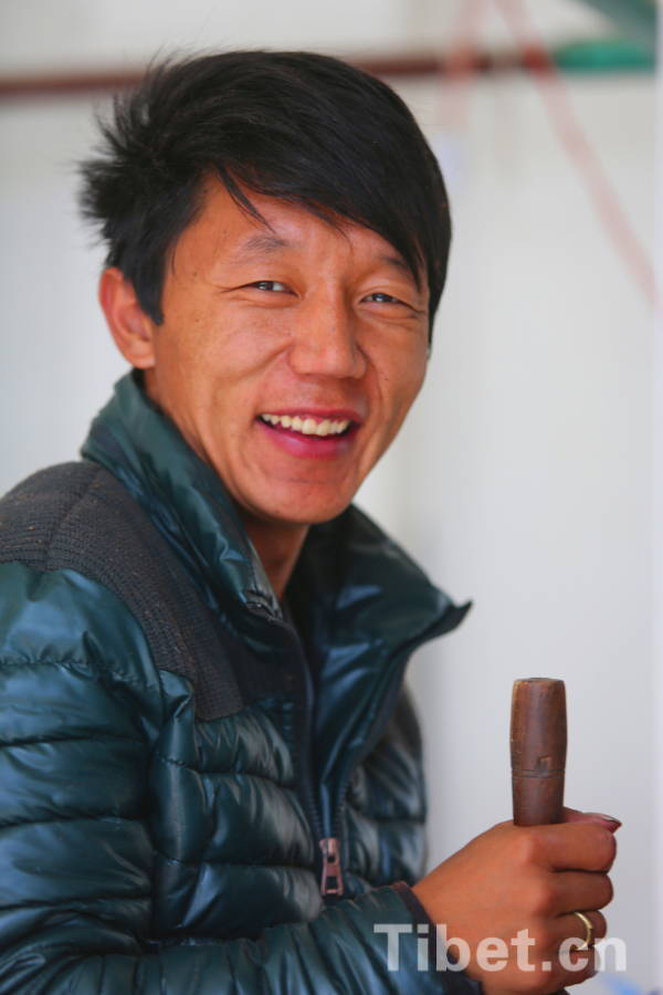 A worker at the Tibet wool factory smiles when he is working. (Photo by Chen Bangxian)