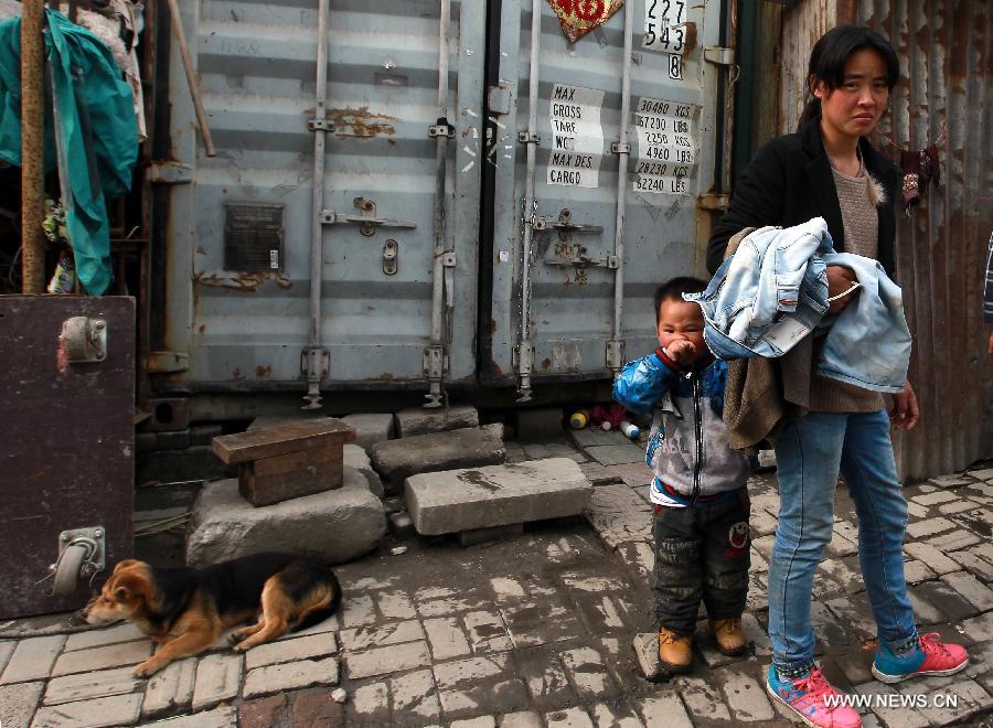 A tenant and her child stand beside their container apartment in Sanlin Town in suburban Shanghai, east China, March 22, 2013. With a monthly rent of 500 yuan (about 80 U.S. dollars) for each container, three migrant worker families settled into their low-cost homes converted from abandoned containers in the metropolis. (Xinhua/Pei Xin)  