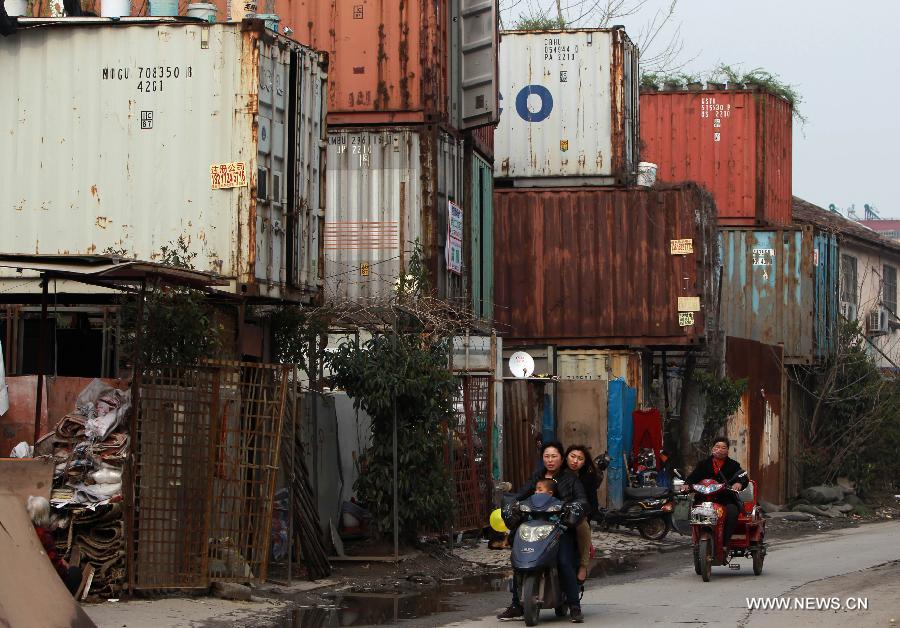 Locals walk past container apartments in Sanlin Town in suburban Shanghai, east China, March 22, 2013. With a monthly rent of 500 yuan (about 80 U.S. dollars) for each container, three migrant worker families settled into their low-cost homes converted from abandoned containers in the metropolis. (Xinhua/Ding Ting)  