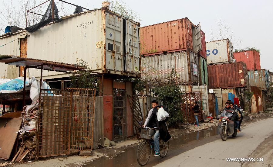 Locals walk past container apartments in Sanlin Town in suburban Shanghai, east China, March 22, 2013. With a monthly rent of 500 yuan (about 80 U.S. dollars) for each container, three migrant worker families settled into their low-cost homes converted from abandoned containers in the metropolis. (Xinhua/Pei Xin)  