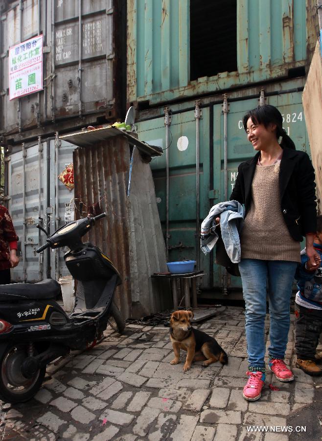 A tenant stands beside her container apartment in Sanlin Town in suburban Shanghai, east China, March 22, 2013. With a monthly rent of 500 yuan (about 80 U.S. dollars) for each container, three migrant worker families settled into their low-cost homes converted from abandoned containers in the metropolis. (Xinhua/Ding Ting) 