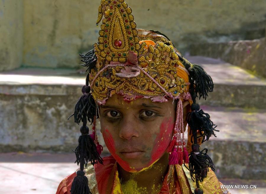 An Indian boy dressed as Lord Krishna gestures with colored face during Latthmaar Holi festival at the Radha Rani temple in Barsana near Mathura city of Indian state Uttar Pradesh, March 21, 2013. (Xinhua/Tumpa Mondal)