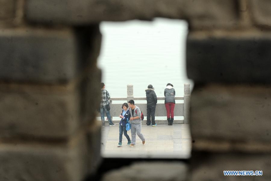 Tourists enjoy themselves on the bank of the Hanjiang River under the old city wall in Xiangyang, central China's Hubei Province, March 21, 2013.  (Xinhua/Li Xiaoguo)