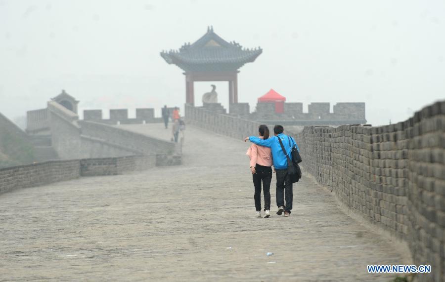 Tourists walk on the ancient city wall in Xiangyang, central China's Hubei Province, March 21, 2013. (Xinhua/Li Xiaoguo)