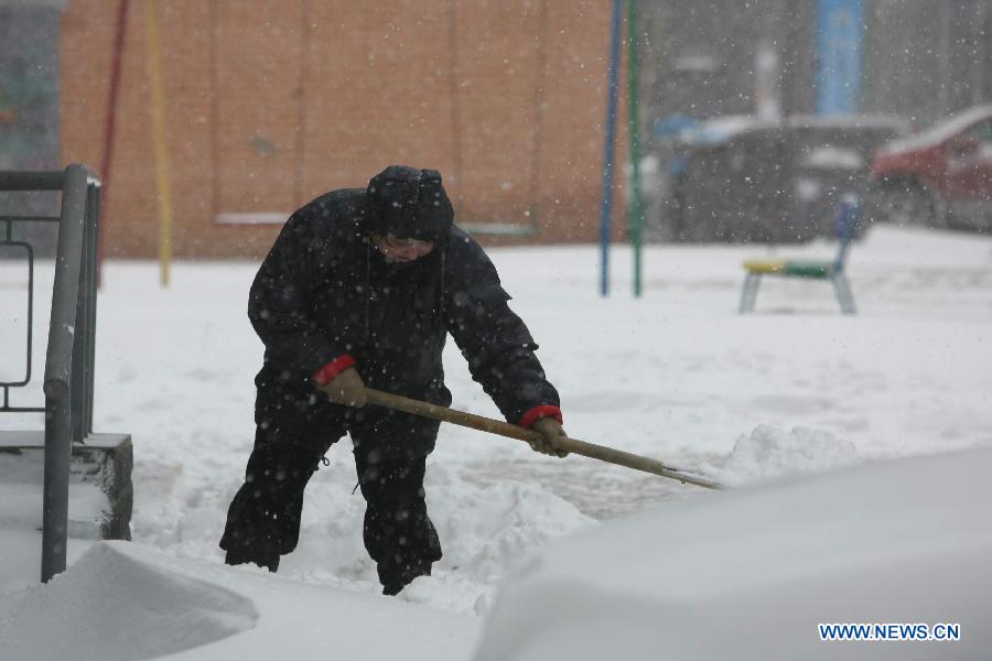 A dustman tries to clear a pavement in heavy snow in Kiev, capital of Ukraine, March 22, 2013. Heavy snow hit Kiev on Friday, disturbing traffic here. (Xinhua/Mu Liming)  