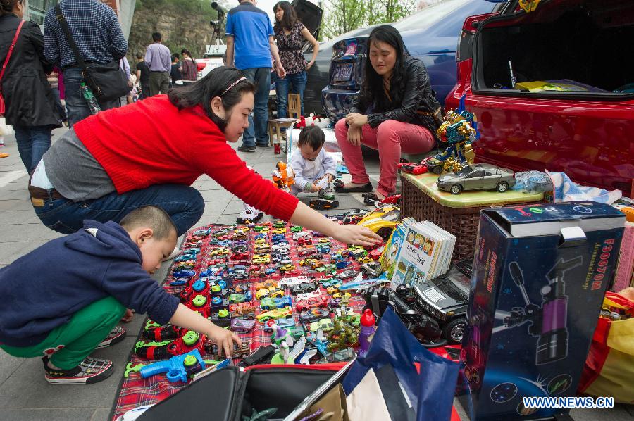 Shoppers choose old toys at a weekend trunk market held by a local auto club at Beibin Road in Chongqing, southwest China's municipality, March 23, 2013. (Xinhua/Chen Cheng) 