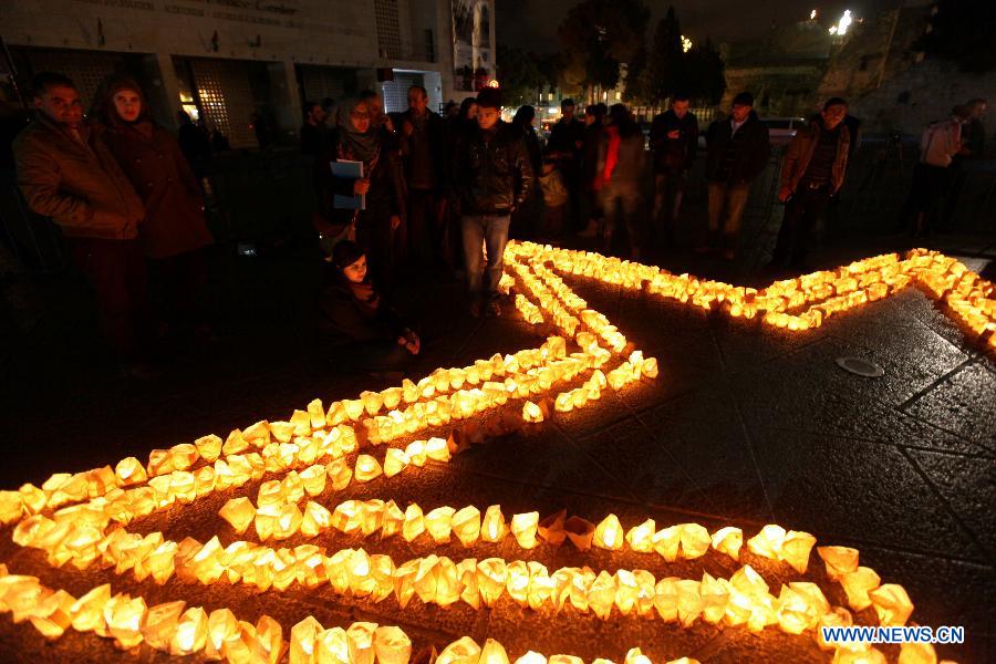 Palestinians gather around candles to mark the "Earth Hour" near the Church of Nativity in the West Bank city of Bethlehem on March 23, 2013. (Xinhua/Luay Sababa) 