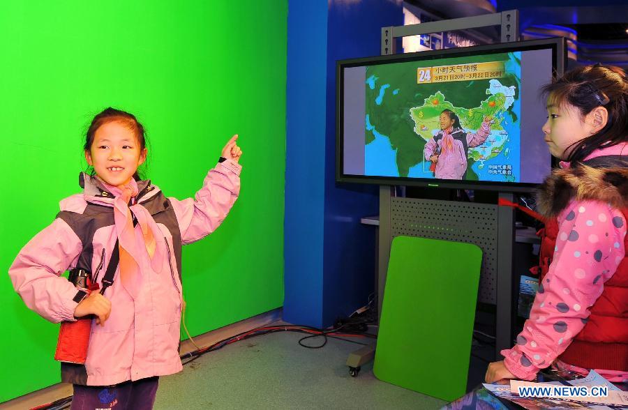 A student simulates a weather forecast hostess on the open day at China Meteorological Administration in Beijing, capital of China, March 23, 2013, the World Meteorological Day. (Xinhua/Chen Yehua) 