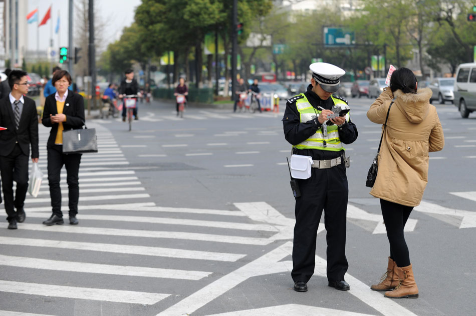A traffic policeman issues a ticket to a jaywalker at a crossing in Hangzhou, east China’s Zhejiang province, March 21, 2013. More than 8, 000 jaywalkers have been fined in Hangzhou since the city launched a traffic law enforcement campaign at the beginning of March. (Xinhua/Ju Huanzong)