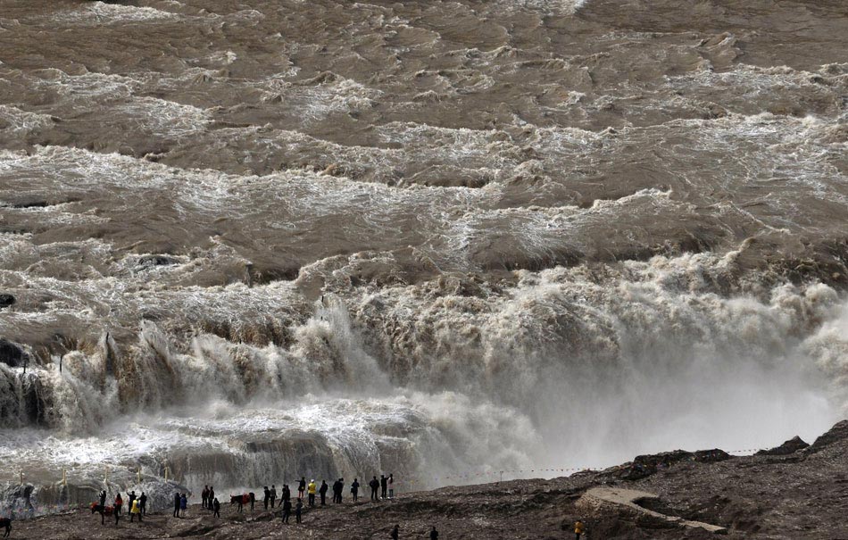 Tourists watch China’s second largest waterfall - Hukou Falls of Yellow River - which embraced the earliest flood season in recent five years, March 18, 2013. (Xinhua/Lyu Jiaming)