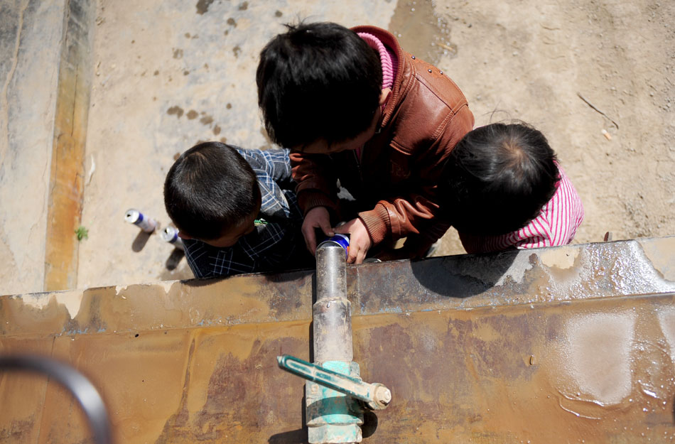 Three boys fill a can with water from a leaked pipe in Baiyin city, northwest China’s Guisu province, March 19, 2013. Affected by less rainfall in autumn and winter, more than 3 million people are suffering from drought. (Xinhua/Zhang Meng)