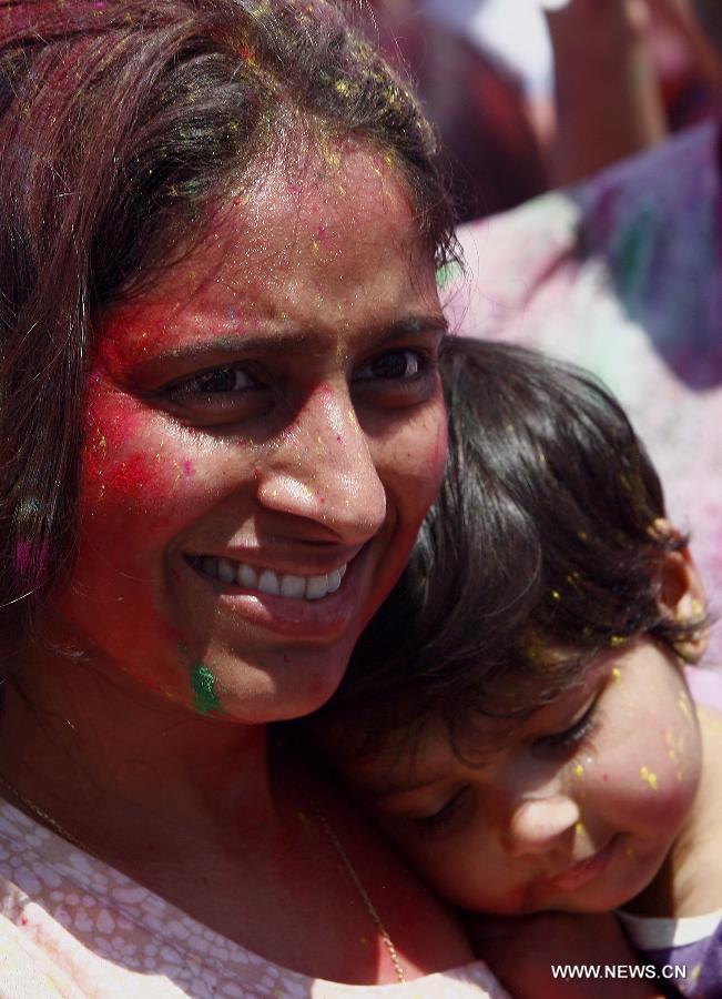 A woman with colored powder on her face carries her sleeping son during the Holi Festival in Pasay City, the Philippines, March 24, 2013. The Holi Festival is one of the major festivals in India, celebrating the turn of the seasons from winter to spring. Also known as the Festival of Colors, it is a fun-filled celebration during which hundreds of people gather to enjoy a day of dancing, eating and throwing colored powder at one another. (Xinhua/Rouelle Umali)