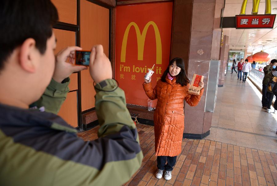 Wang Xiao takes a souvenir photo for his wife Hou Jin outside the McDonald's restaurant at Chang'an Market, where he tasted the American fast-food for the first time at the age of 11, in Beijing, capital of China, March 24, 2013. Opened in 1993 as the second outlet of the American fast-food giant in Beijing, the Chang'an Market McDonald's made indelible impressions on locals. Due to reconstruction and adjustment of the market, the outlet discontinued its business Sunday. (Xinhua/Li Xin)