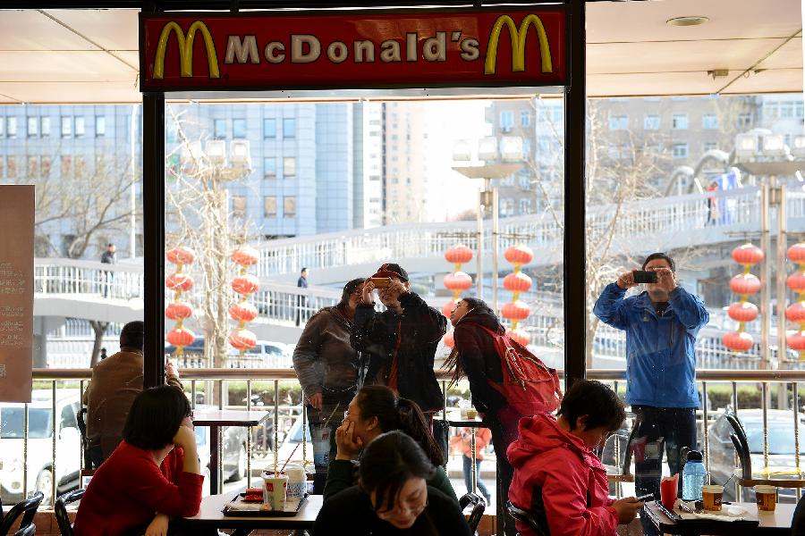 Customers take souvenir photos outside the McDonald's restaurant at Chang'an Market in Beijing, capital of China, March 24, 2013. Opened in 1993 as the second outlet of the American fast-food giant in Beijing, the Chang'an Market McDonald's made indelible impressions on locals. Due to reconstruction and adjustment of the market, the outlet discontinued its business Sunday. (Xinhua/Li Xin)