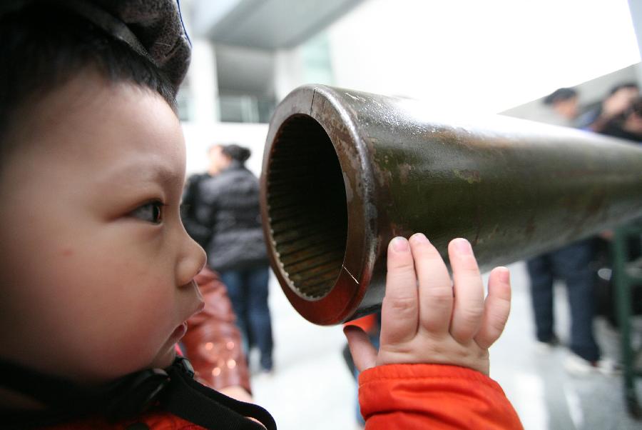 A boy watches a gun barrel at the weapon museum of Nanjing University of Science and Technology (NJUST) in Nanjing, capital of east China's Jiangsu Province, March 24, 2013. The NJUST opened to public to celebrate its 60th anniversary Sunday. The weapon museum collects about 6,000 weapons since the First World War. (Xinhua/Wang Xin)