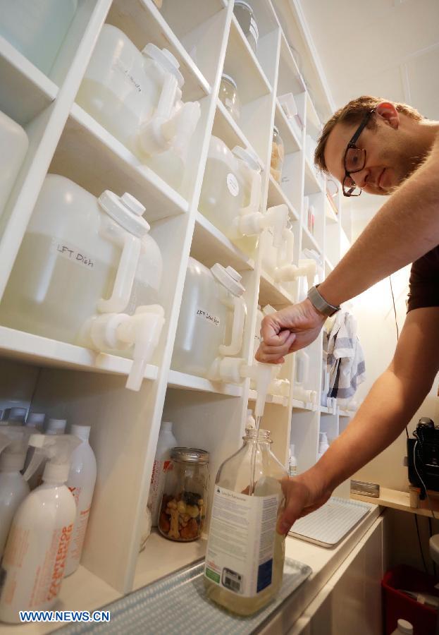 A staff member refills an old plastic bottle with cleanser sold at a refill store in Vancouver, Canada. March 23, 2013. The refill store provides nearly 100 kinds of soaps and cleaning products, encouraging customers to bring old empty bottles for refill in order to reduce plastic waste. (Xinhua/Liang Sen) 