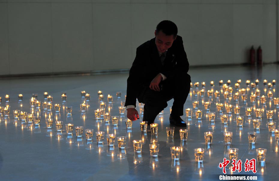 A staff member lights candles in the shape of “60” to mark Earth Hour in a shopping mall in Shenyang at night of March 23. (CNS/Yu Haiyang )