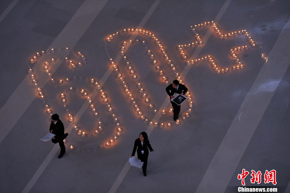 Hundreds of candles are lit in the shape of “60+” to mark Earth Hour in a shopping mall in Shenyang at night of March 23. “60+” signifies a global effort by the World Wide Fund for Nature to save 60 tons of carbon dioxide by darkening cities for one hour. (CNS/Yu Haiyang )
