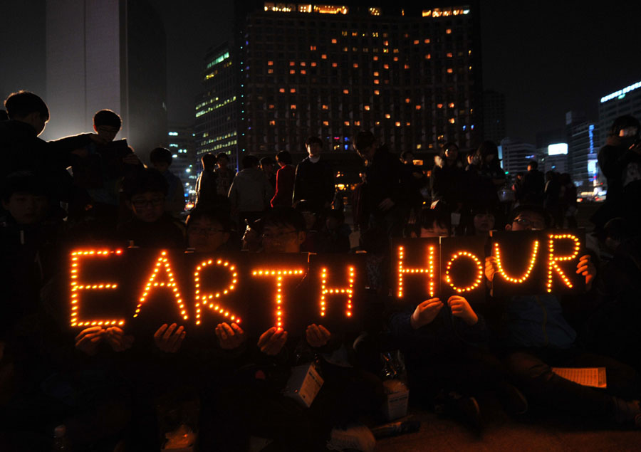 South Korean students hold an Earth Hour LED display during the 7th annual Earth Hour global warming campaign in Seoul on March 23, 2013. One minute brightly lit, the next plunged into darkness -- iconic landmarks around the world will cut their lights on March 23 for the "Earth Hour" campaign against climate change. (Xinhua/ AFP) 