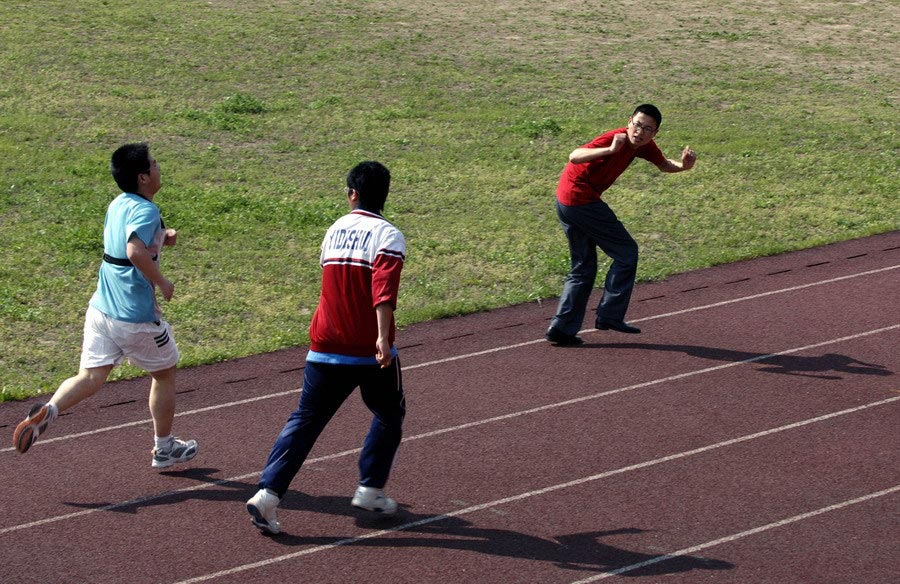 Students were taking their PE exam in the No.1 Elementary Junior School on Apr. 15, 2009. Their anxious teacher can be seen sparing no effort to voice his support to those who get behind in the 1000-meter race. The exam, requiring a lot of stamina, turned out to be a stressed and overpowering one, foregoing its original goal of enhancing students' physical health. (Zhejiang Daily/Chu Yongzhi)