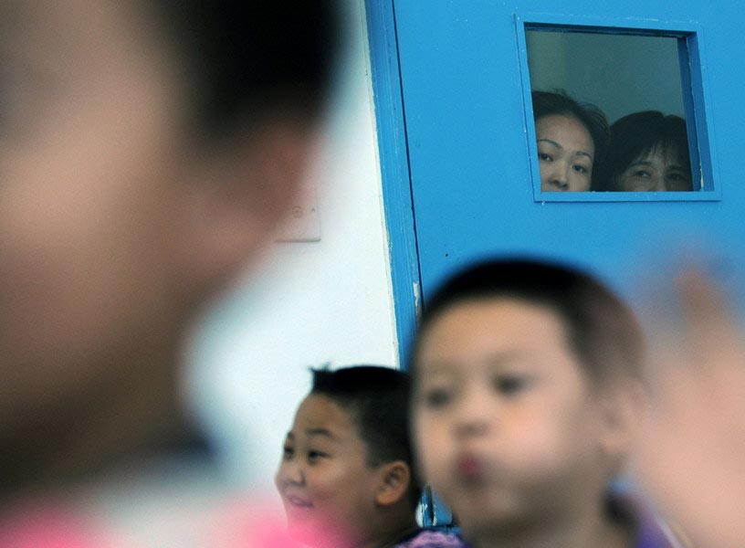 On July 12, 2010, outside the classrooms of the preschool in Jiaxing Youth Palace, Zhejiang, parents keep a close watch on their children through the windows. Each and every move of the children can affect their parents' mood. (Zhejiang Daily/Chu Yongzhi)