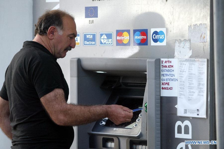 A Cypriot man uses an ATM outside a bank in Nicosia March 25, 2013. Ordinary Cypriots are numb and worried on the aftermath of the new Eurogroup's agreement, which offers a harsh 10 billion euro bailout deal to Cyprus, including the radical reshaping of the Cypriot banking system. Depositors will lose a large portion of their money exceeding 100,000 euros in the bank. (Xinhua/Marios Lolos)