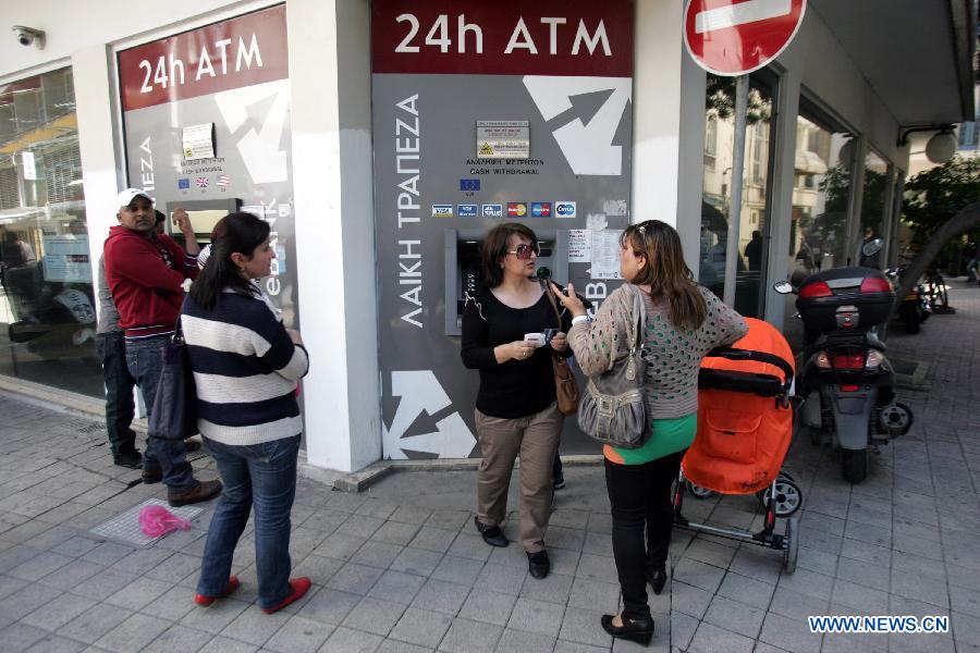 Cypriots use ATMs in Nicosia March 25, 2013. Ordinary Cypriots are numb and worried on the aftermath of the new Eurogroup's agreement, which offers a harsh 10 billion euro bailout deal to Cyprus, including the radical reshaping of the Cypriot banking system. Depositors will lose a large portion of their money exceeding 100,000 euros in the bank. (Xinhua/Marios Lolos) 