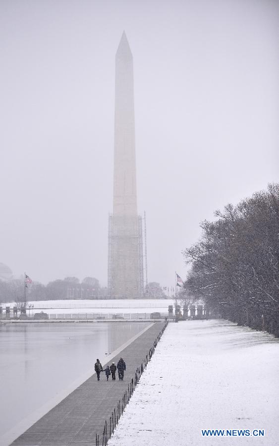 A family walk amid snowfall near the Washington Monument at the National Mall in Washington D.C., capital of the United States, on March 25, 2013. (Xinhua/Zhang Jun)