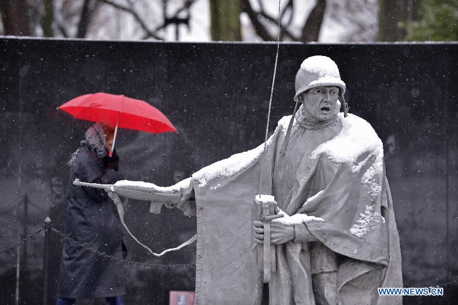 A tourist walks past a snow-covered soldier statue at the National Mall in Washington D.C., capital of the United States, on March 25, 2013. (Xinhua/Zhang Jun)