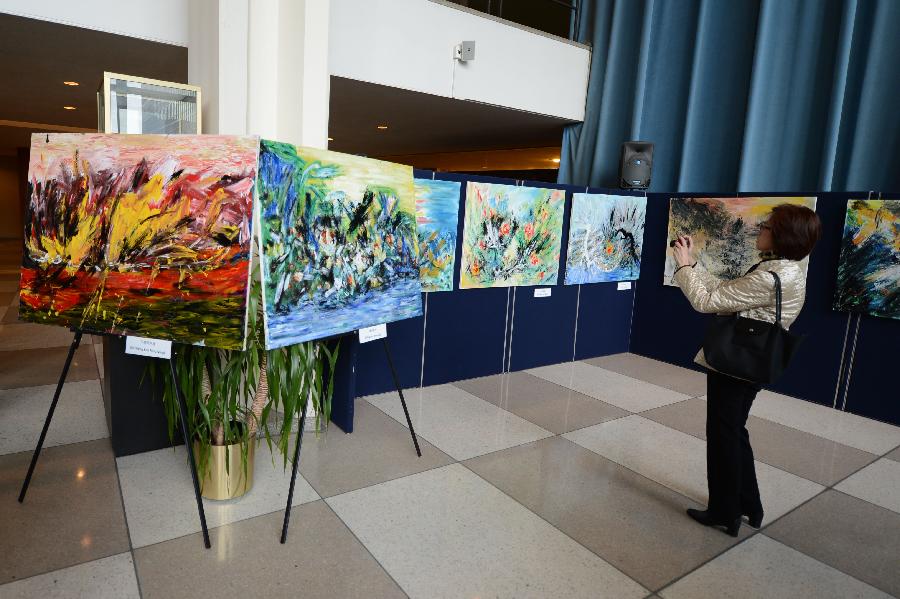 A visitor takes pictures of oil paintings on display during an exhibiton entitled "A Semblance Great: The Shadow of a Shade", at the United Nations headquarters in New York, the United States, on March 26, 2013. The exhibition consisted of 38 oil paintings by artist Li Hongtao, who was renowned for his unique style of painting. (Xinhua/Niu Xiaolei) 