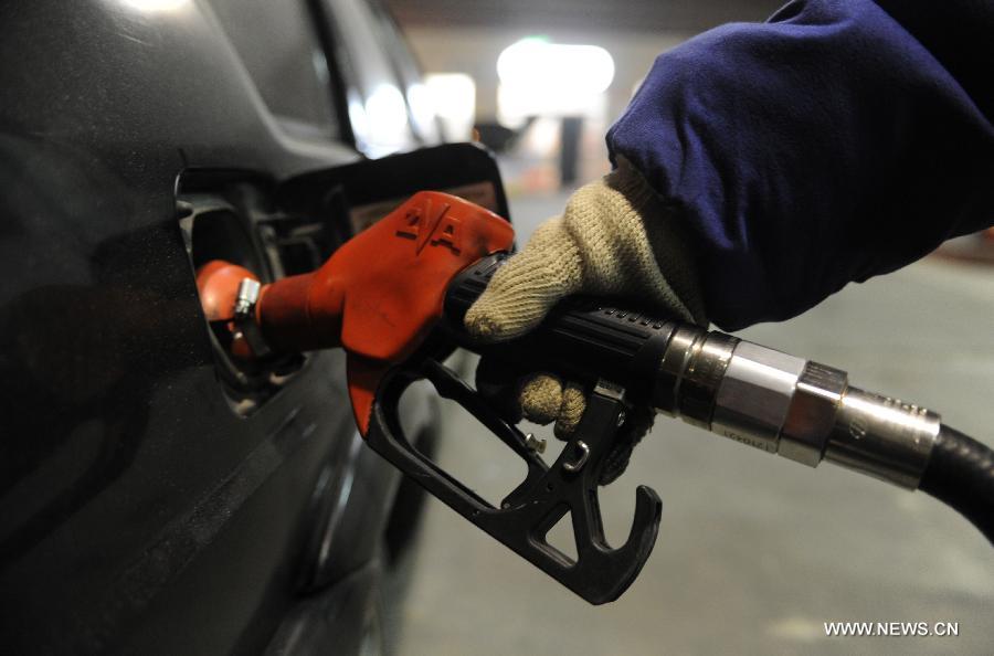 A staff member refuels a car at a gas station in Shijiazhuang, north China's Hebei Province, March 27, 2013. China cut the retail prices of gasoline by 310 yuan (49.43 U.S. dollars) per tonne and diesel by 300 yuan per tonne starting Wednesday. The National Development and Reform Commission (NDRC) also announced a new pricing system which will adjust the prices of oil products every 10 working days to better reflect changes in the global oil market. (Xinhua/Wang Xiao) 
